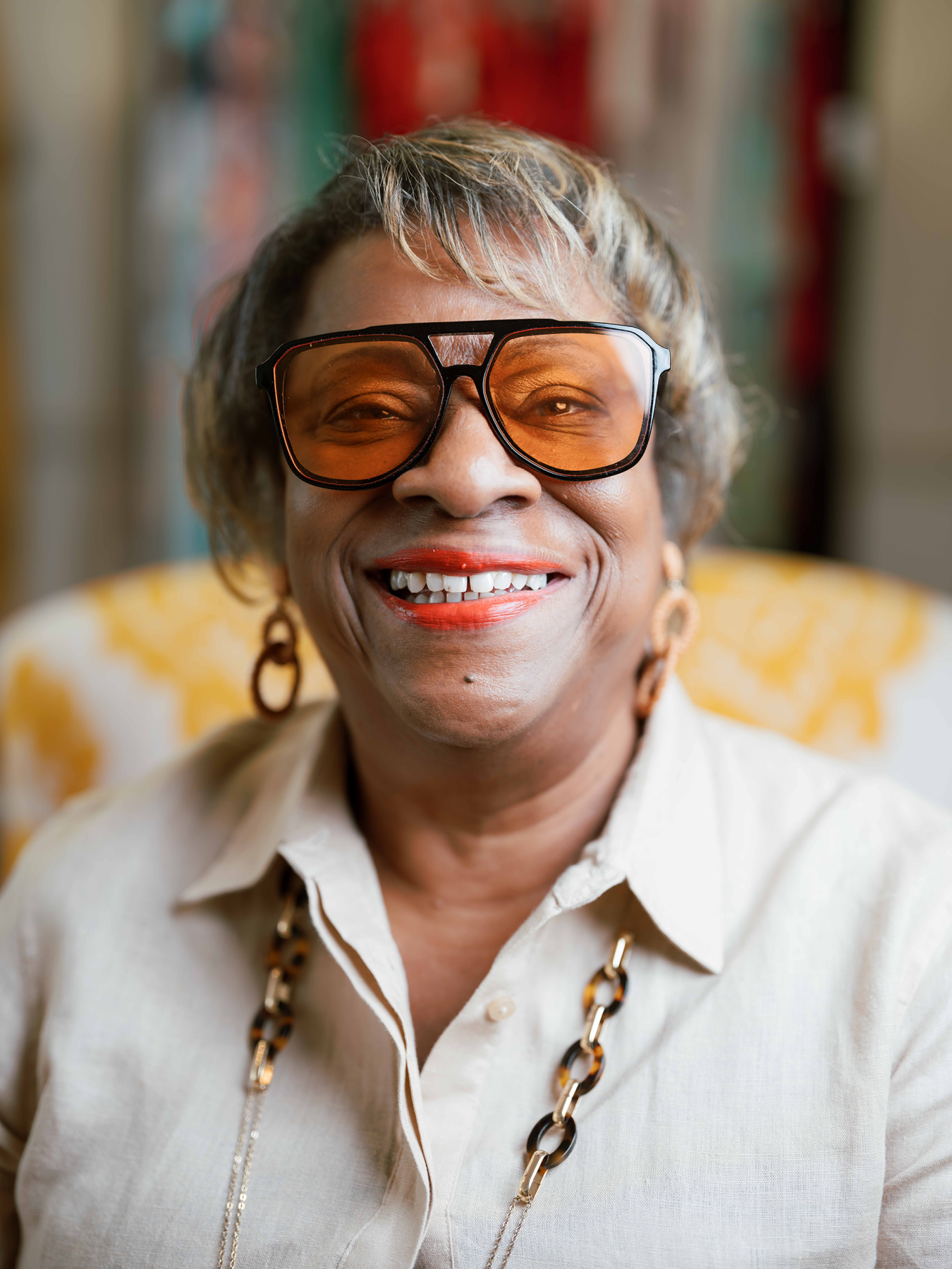 A woman wearing tinted glasses against a colorful background.